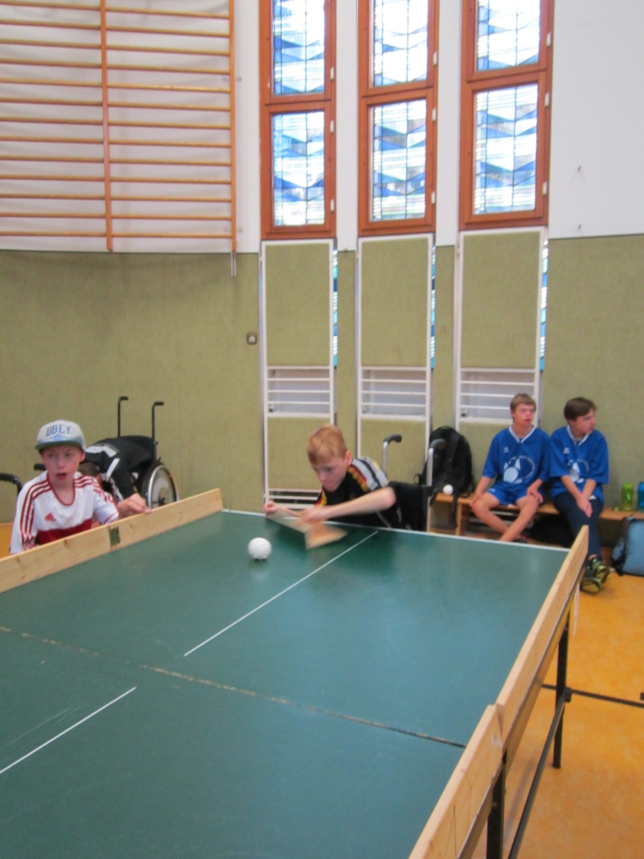 Fynn, Brianna und Juliana spielen in der Turnhalle an der Platte warm.