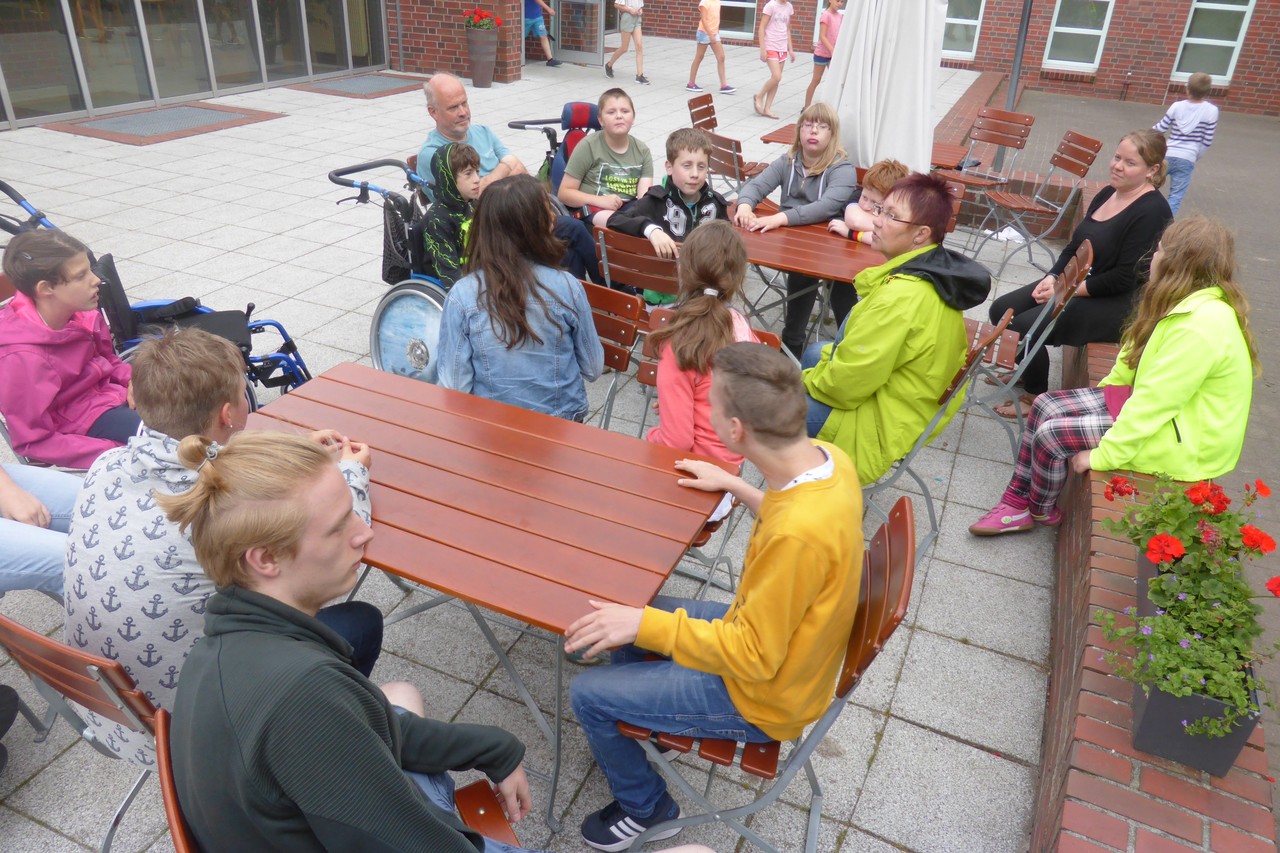 Schüler und Lehrer sitzen vor der Jugendherberge