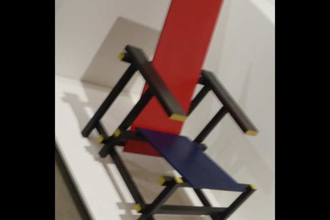 Ein Stuhl in rot, gelb, blau aus einfachen Latten zusammengesetzt